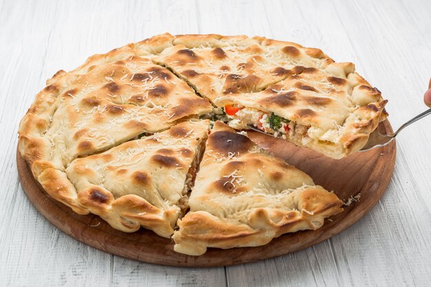 Pastel con carne, verduras y queso sobre una superficie de madera