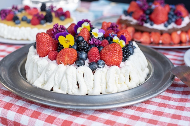 Pastel casero con bayas de crema batida y postre de flores comestibles para vacaciones