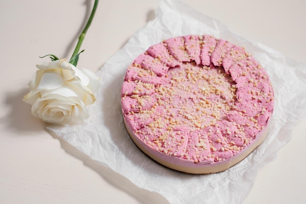 Pastel casero con nueces sobre papel pergamino con rosa blanca Entrega de alimentos Horneado casero Vista lateral Deliciosa tarta redonda con nueces sobre la mesa de madera