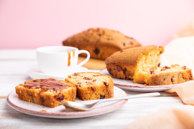 Pastel casero con pasas, almendras, caramelo suave sobre una superficie blanca y rosa