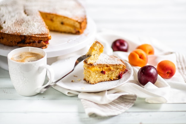 Pastel casero.Preparación de alimentos.Pastel dulce de frutas con albaricoques y ciruelas. Mesa servida Con café y pastel. Articulos de cocina