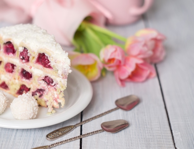 Un pastel con cerezas y tulipanes rosas sobre una mesa de madera blanca