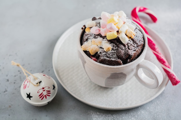 Pastel de chocolate de año nuevo cocinado en horno microondas en taza sobre textura de superficie gris vintage