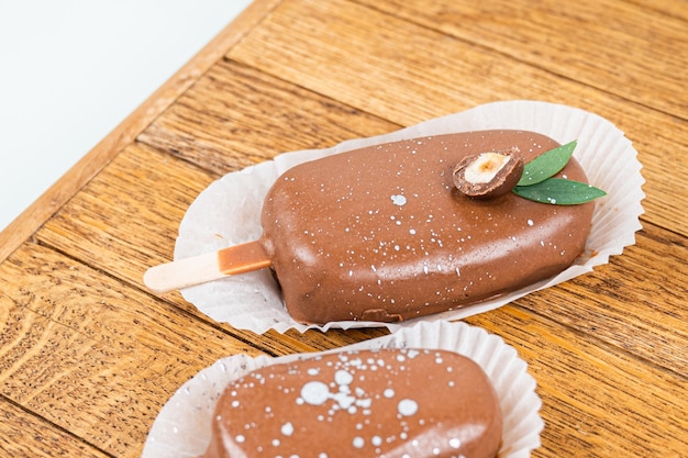 Pastel de chocolate aparece en forma de helado en un palo En una vista lateral del soporte de madera Dulces de comida conceptual