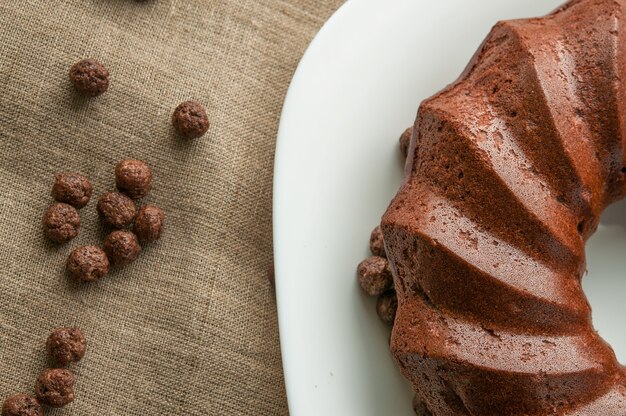 Pastel de chocolate con bolas de chocolate y plato blanco sobre lienzo.