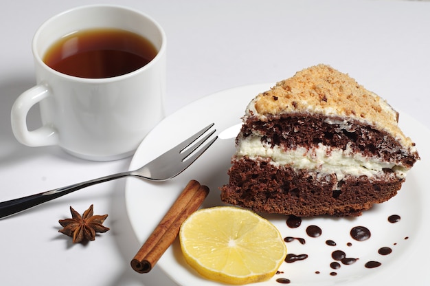 Pastel de chocolate casero con crema batida y una taza de té en la mesa de madera antigua