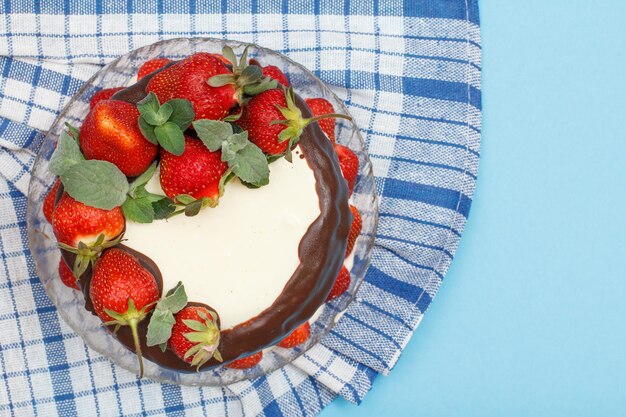 Pastel de chocolate casero decorado con fresas frescas y hojas de menta en placa de vidrio