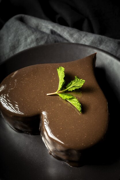 Pastel de chocolate casero en forma de corazón sobre fondo negro