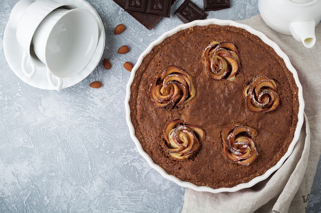 Pastel de chocolate casero con frangipane y flores de manzano sobre hormigón gris claro