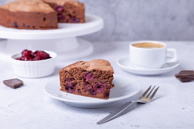 Pastel de chocolate y cerezas En el fondo hay un pastel, una taza de café, cerezas y trozos de chocolate.