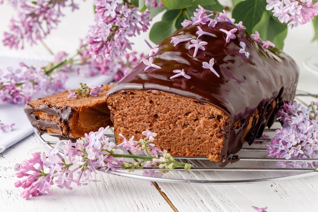 Pastel de chocolate clásico sobre una mesa blanca con flores.