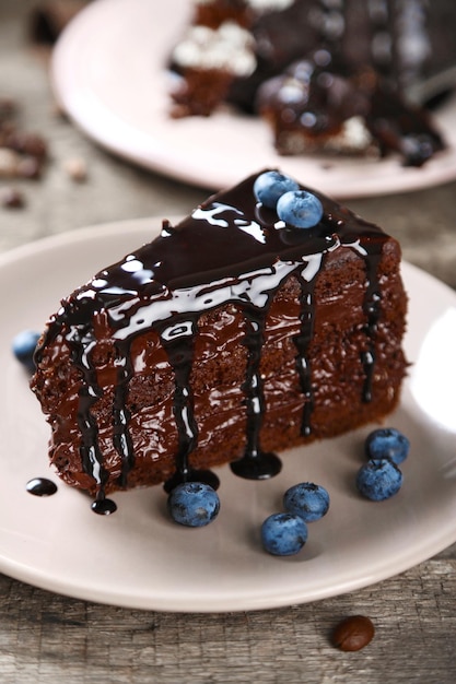 Pastel de chocolate con crema de chocolate y arándanos frescos en un plato sobre fondo de madera