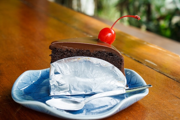 Pastel de chocolate decorado con cerezas en platos azules y cuchara