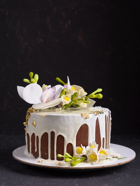 Pastel de chocolate decorado con flores y glaseado blanco. Copyspace