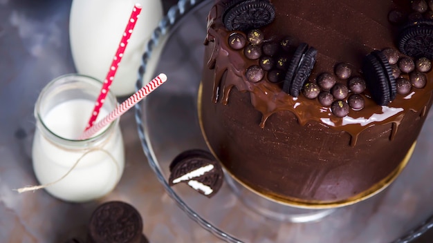 Pastel de chocolate decorado con galletas junto a tarros de leche.