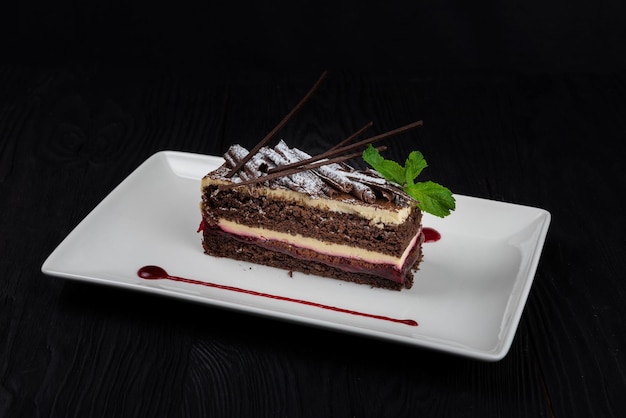 Pastel de chocolate decorado con hojas de menta sobre fondo negro