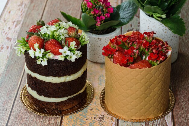 Pastel de chocolate desnudo junto al pastel de vestido cubierto con tablero texturizado. Decorado con fresas y flores de Kalanchoe.
