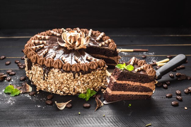 Pastel de chocolate dulce con crema sabrosa en el fondo de madera negra