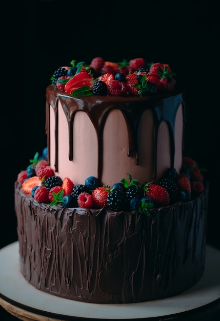 Pastel de chocolate de frutas en soporte de madera en negro.