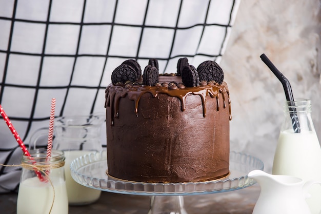 Pastel de chocolate con galletas en un soporte de vidrio entre los recipientes.