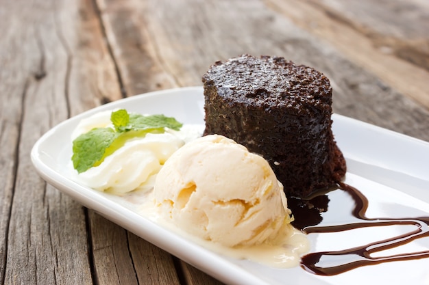 Pastel de chocolate con helado de pasas de ron y crema batida en un plato blanco