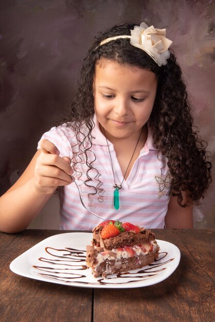 Pastel de chocolate, linda chica con hermoso trozo de pastel de chocolate con fresas, enfoque selectivo.