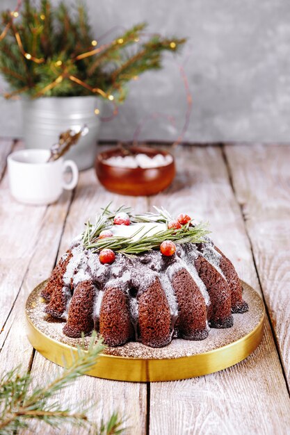 Pastel de chocolate navideño decorado con frutos del bosque y romero