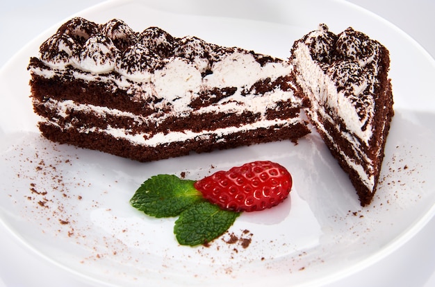 Pastel de chocolate en un plato blanco con fresas y menta