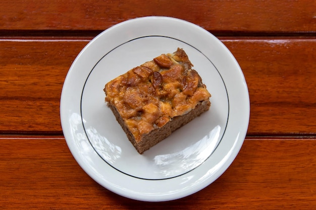 El pastel de chocolate en un plato blanco se ve apetitoso colocado en una mesa de madera