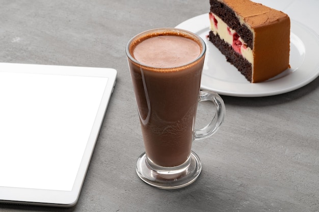 Pastel de chocolate con taza de cacao en la mesa