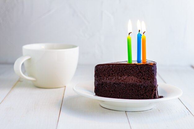Pastel de chocolate con velas en el plato blanco.