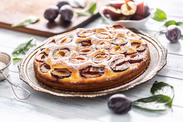 Pastel de ciruela casero en plato vintage sobre mesa de madera. Pastel de ciruelas con azúcar en polvo.