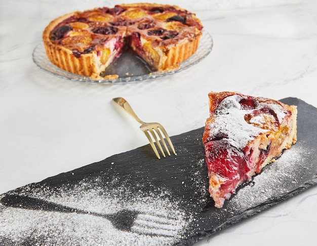 Pastel de ciruela con kinaman espolvoreado con azúcar en polvo sobre piedra negra