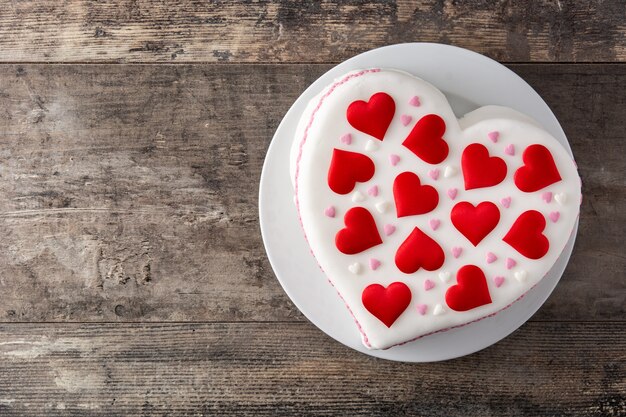 Pastel de corazón para el día de San Valentín, decorado con corazones de azúcar en la mesa de madera