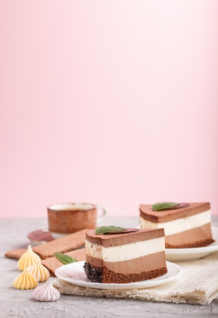 Pastel con crema de chocolate con leche souffle con taza de café en una pared gris y rosa. Vista lateral, copia espacio.