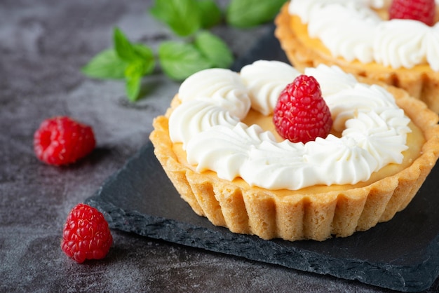 Pastel cremoso de tarta de queso con frambuesas en una mesa gris