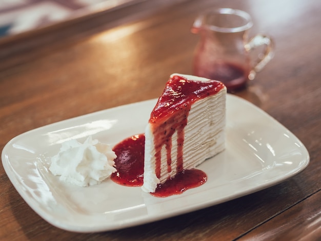 Pastel de crepe francés con salsa de fresa jugosa en café.