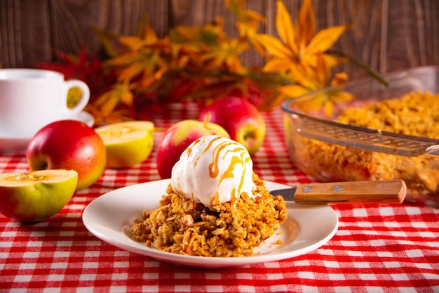 Pastel crujiente de cramble de manzana casero en un plato blanco con hojas de otoño en el fondo