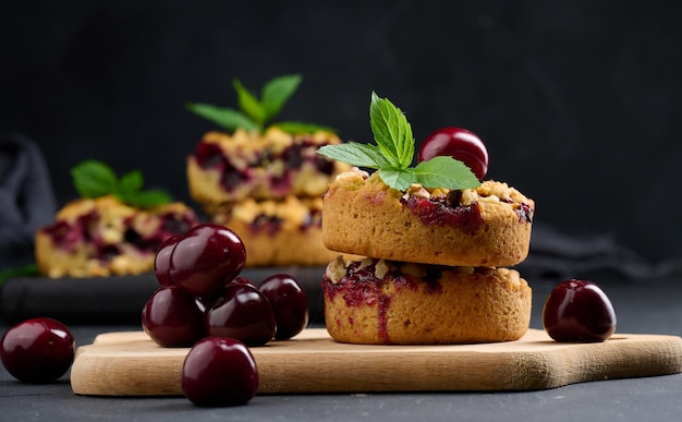 Pastel de crumble de porción con cerezas en una tabla de madera decorada con hojas de menta verde