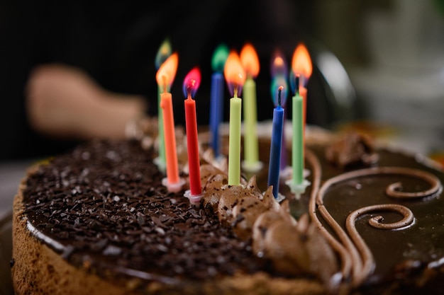 Pastel de cumpleaños de chocolate con velas encendiendo velas en el pastel