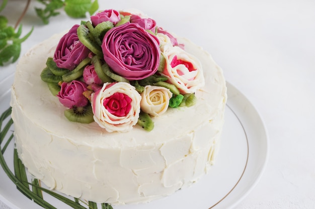 Pastel de cumpleaños con flores rosa sobre fondo blanco.