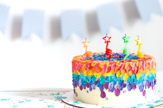 Pastel de cumpleaños multicolor decorado con crema y velas. Concepto de fiesta de cumpleaños.