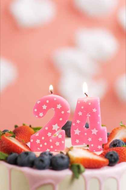 Pastel de cumpleaños número 24 Hermosa vela rosa en pastel sobre fondo rosa con nubes blancas Primer plano y vista vertical