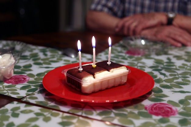 pastel de cumpleaños en un plato rojo con tres velas