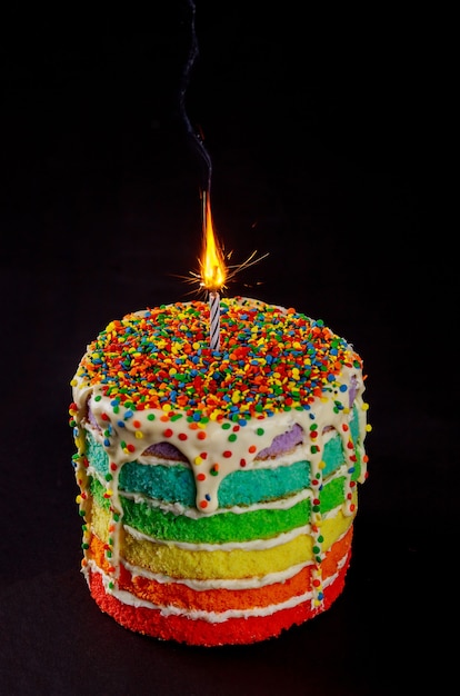 Pastel de cumpleaños con vela encendida y brillo. De cerca.