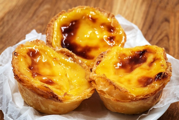 Pastel de nata ou tarte de ovo português em um fundo marrom de madeira Pastel de Belem é uma pequena tarte com uma crosta de doce puff crocante e um recheio de creme de creme doce sobremesa