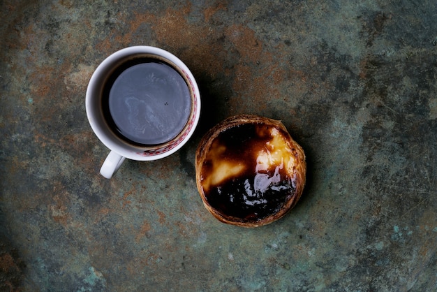 Pastel de nata. Torta de ovo de sobremesa tradicional portuguesa e café sobre fundo de metal rústico. Vista do topo
