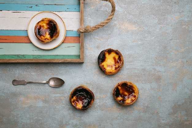 Pastel de Nata. Traditionelles portugiesisches Dessert, Eierkuchen auf dem Holztablett über rustikalem Hintergrund. Draufsicht