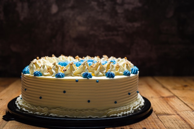 Pastel decorado con flores de queso crema azul y pastel de nuez agrietada sobre mesa de madera