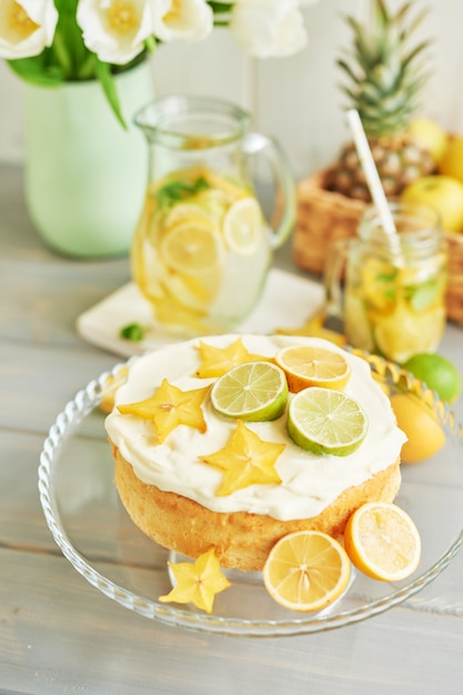 Foto pastel desnudo con limones y limas, limonada, frutas y flores de tulipán